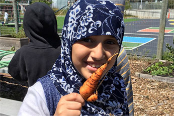 Young girl smiling with fresh carrot